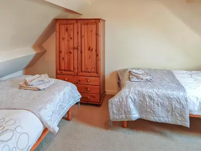 a bedroom with two beds and a wooden cabinet at Arthfan in Llanelltyd