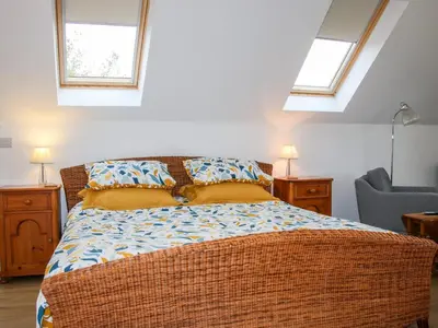 a bedroom with a wicker bed and two windows at Gerry's Place in Church Stretton