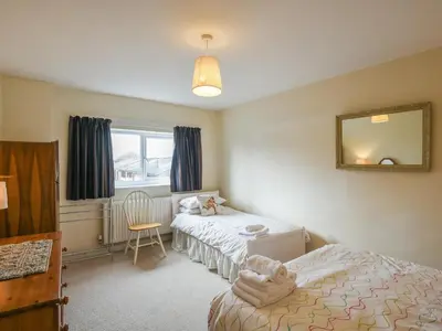 a bedroom with two beds and a mirror and a chair at Garth Ucha in Llanyblodwel
