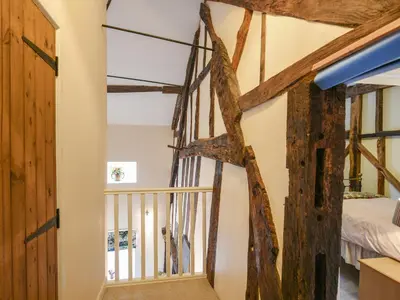 a staircase in a room with wooden beams at Garth Ucha in Llanyblodwel