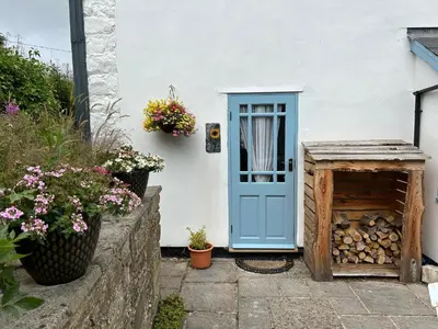 a blue door on a white house with flowers at Y Felin Bed and Breakfast and Smallholding in Caersws