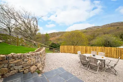 a patio with a table and chairs and a stone wall at 3 Bed in Barmouth oc-wah701 in Barmouth