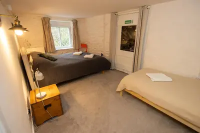 a bedroom with two beds and a door with a window at The Coach House in Llangollen