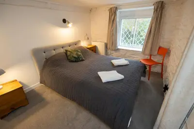 a bedroom with a bed and a chair and a window at The Coach House in Llangollen