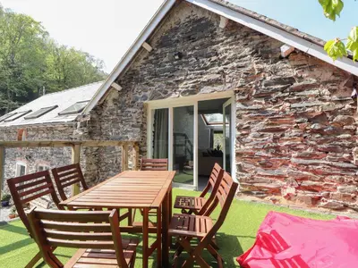 a wooden table and chairs in front of a stone cottage at The Coach House in Llangollen