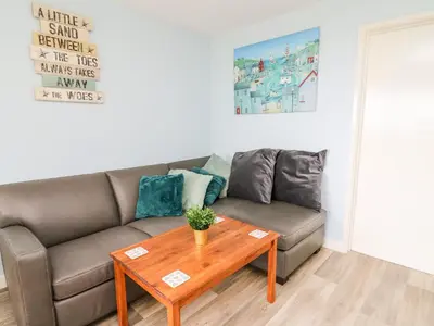 a living room with a couch and a table at Cwtsh Cragen in New Quay