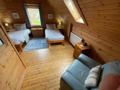 a room with two beds and a couch in a cabin at Luxury 3 bedroom, 3 bathroom lodge with hot tub in Llanbedr
