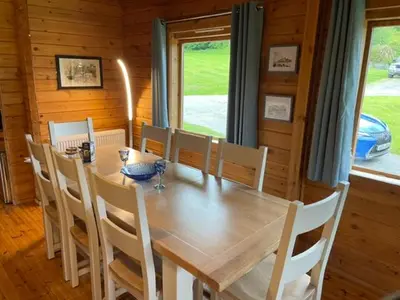 a dining room with a wooden table and chairs at Luxury 3 bedroom, 3 bathroom lodge with hot tub in Llanbedr