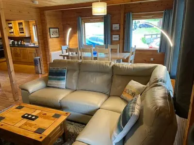 a living room with a couch and a table at Luxury 3 bedroom, 3 bathroom lodge with hot tub in Llanbedr