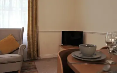 a living room with a couch and a table and a tv at Meadow Terrace in Shrewsbury