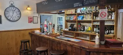 a bar with stools and a clock on the wall at Dinas Castle Inn (The Dragons Back) in Brecon