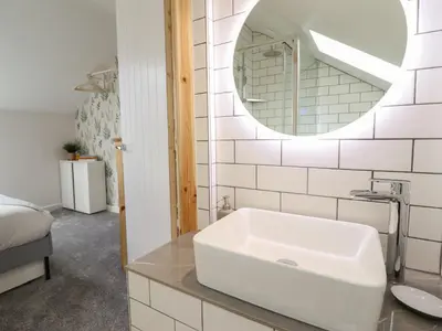 a white bathroom with a sink and a mirror at Little Nook in Corwen
