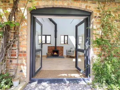 an open door into a living room with a fireplace at Little Nook in Corwen