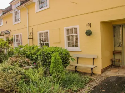 a yellow house with a bench in front of it at 138C Old Star and Garter Mews in Ludlow