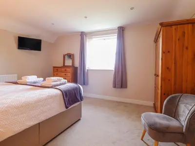 a bedroom with a bed and a window and a chair at Ty Cerrig in Dyffryn