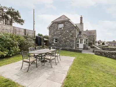 a patio with a table and chairs in front of a house at Ty Cerrig in Dyffryn