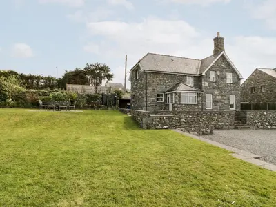 an old stone house with a grass yard at Ty Cerrig in Dyffryn