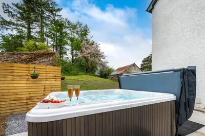 a hot tub with champagne glasses and a bowl of fruit at 3 Bed in Bethlehem oc-waw219 in Llangadog