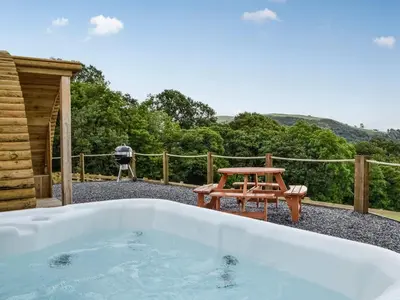 a hot tub and a picnic table on a patio at Valley View - Uk34178 in Cilycwm