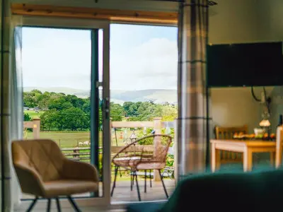 a room with a door open to a patio with a table and chairs at Cwtch Enrico - Uk39064 in Scyborycoed