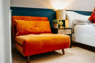 an orange chair in a bedroom next to a bed at Boutique Shrewsbury Suites in Shrewsbury