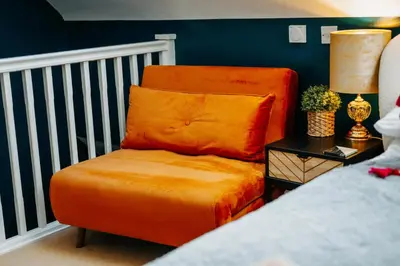 an orange chair sitting next to a bed at Boutique Shrewsbury Suites in Shrewsbury
