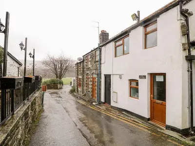 an empty street with a white building on the side at Triangle Inn Coachouse in Rhayader