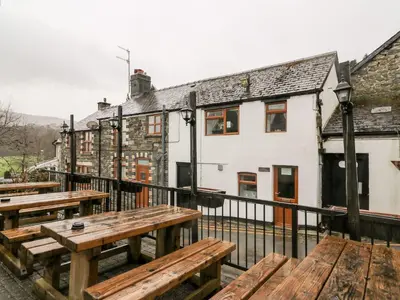 a group of wooden benches on a balcony with buildings at Triangle Inn Coachouse in Rhayader