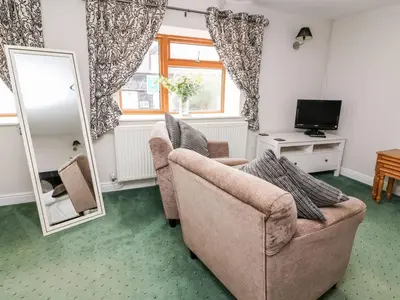 a living room with two chairs and a mirror at Triangle Inn Coachouse in Rhayader
