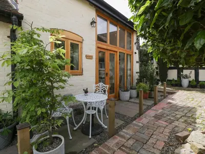 a patio with a table and chairs in front of a house at The Cart Barn in Leominster