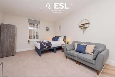 a bedroom with a bed and a couch and a chair at Studio 1, First Floor Town Centre Apartment in Shrewsbury