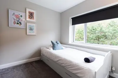 a bedroom with a white bed and a window at Stunning Pet-Friendly Home with Hot Tub less than one minute walk from Barmouth Beach in Barmouth