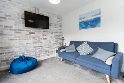 a living room with a blue couch and a brick wall at Stunning Pet-Friendly Home with Hot Tub less than one minute walk from Barmouth Beach in Barmouth