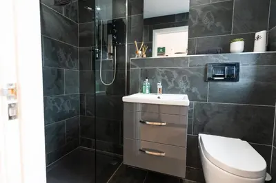 a bathroom with a shower and a toilet and a sink at Stunning Pet-Friendly Home with Hot Tub less than one minute walk from Barmouth Beach in Barmouth