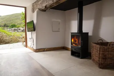 a living room with a stove in a room with a view at Snowdonia Holiday Cottage in Bala