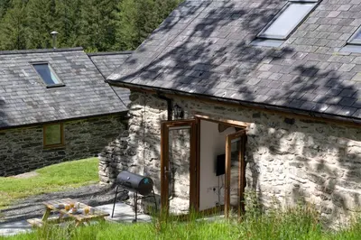 a stone house with a door and a stove at Snowdonia Holiday Cottage in Bala