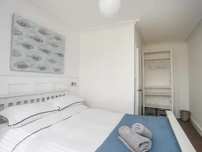 a white bedroom with towels on a bed at Arran House in Barmouth