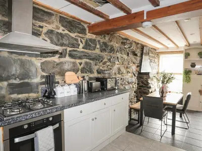 a kitchen with a stove and a stone wall at Arran House in Barmouth