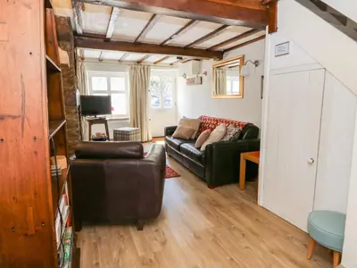 a living room with a leather couch and a tv at Chancery Cottage in Hay-on-Wye