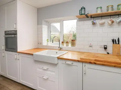 a kitchen with white cabinets and a sink and a window at Cysgod Y Coed in Machynlleth