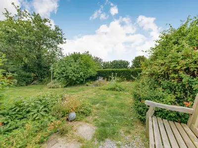 a garden with a wooden bench in the grass at Cysgod Y Coed in Machynlleth