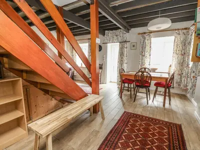 a living room with a table and a wooden staircase at Cysgod Y Coed in Machynlleth