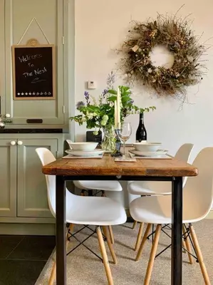 a dining room table with white chairs and a wreath on the wall at The Nest, central Ludlow one bed apartment in Ludlow
