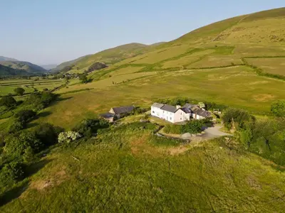 an aerial view of a house in a field at Romantic Snowdonia Cottage with Hot tub, sea & mountain views in Tywyn