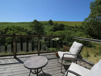 a wooden deck with two chairs and a table at Golwg Las in Llanwrda