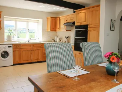 a kitchen with a wooden table and blue chairs at The Stables in Shrewsbury
