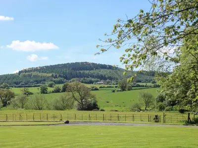 a field of green grass with a hill in the background at The Stables in Shrewsbury