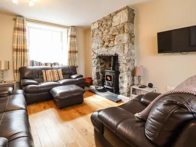 a living room with leather furniture and a stone fireplace at Artro View in Llanbedr