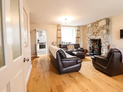 a living room with leather furniture and a stone fireplace at Artro View in Llanbedr