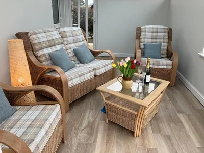 a living room with wicker chairs and a table with flowers at Berwyn View in Welshpool